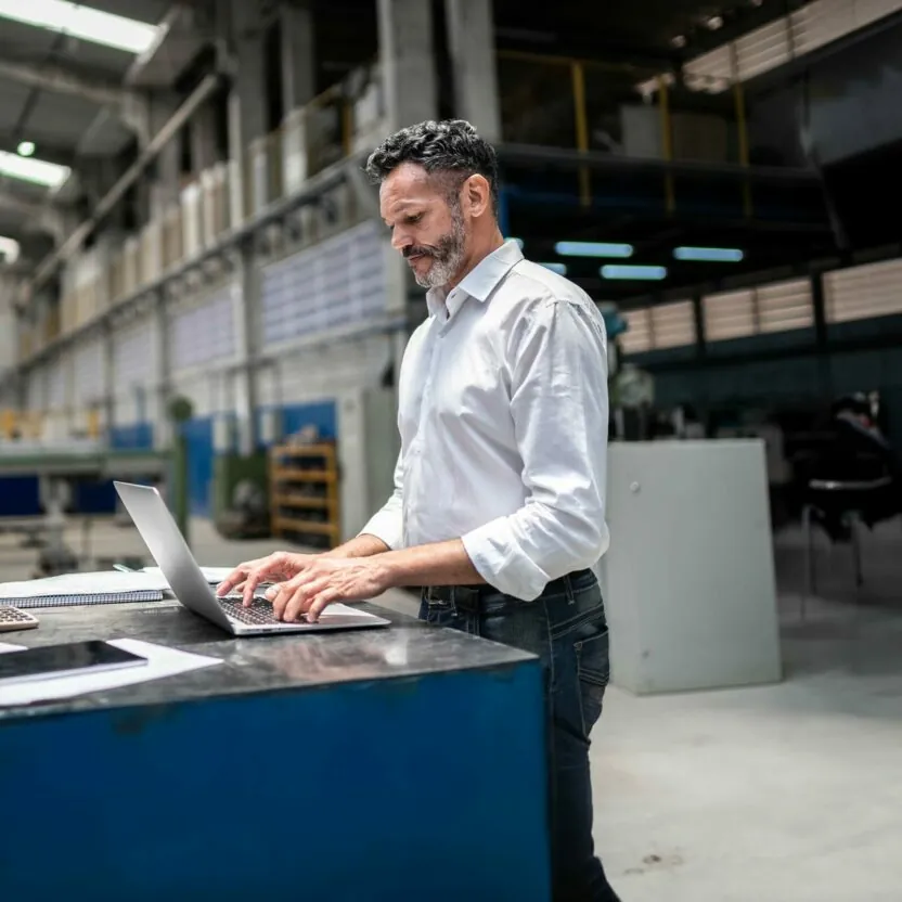 Mature businessman using laptop in a factory Mature businessman using laptop in a factory