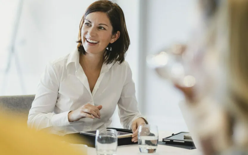 smiling businesswoman with tablet in meeting | valantic digital legal record in SAP